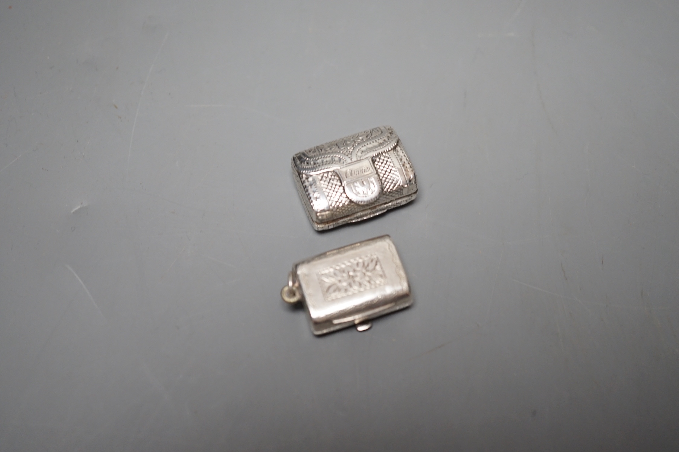 A George III engraved silver vinaigrette, modelled as a handbag, John Lawrence & Co, Birmingham, 1817, 23mm engraved 'Anne' and a similar William IV silver vinaigrette, Thomas Simpson Jn, Birmingham, 1831, 21mm.
